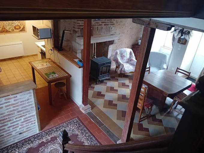 Le rez-de-chaussée vu depuis l'escalier : carreaux de ciment, poêle en fonte, coin repas et cuisine